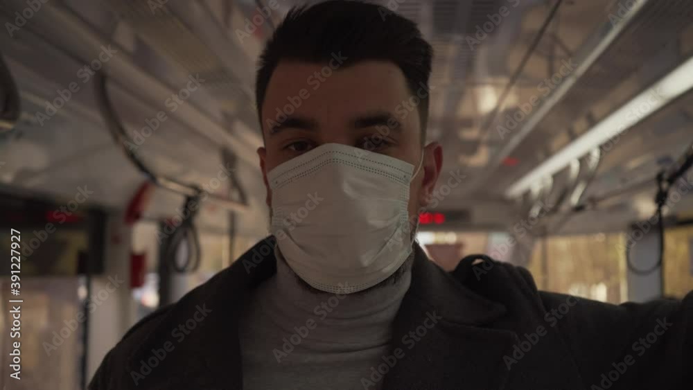 Close up of young man put on medical mask in trolleybus while look in ...