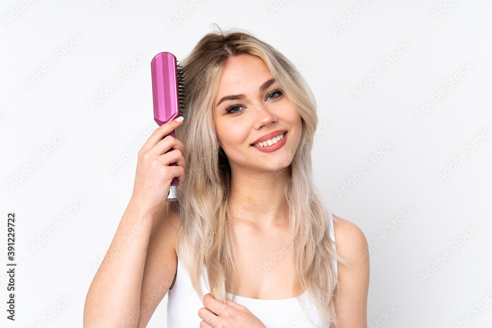 Teenager blonde girl over isolated white background with hair comb Teenager blonde girl over isolated white background with hair comb