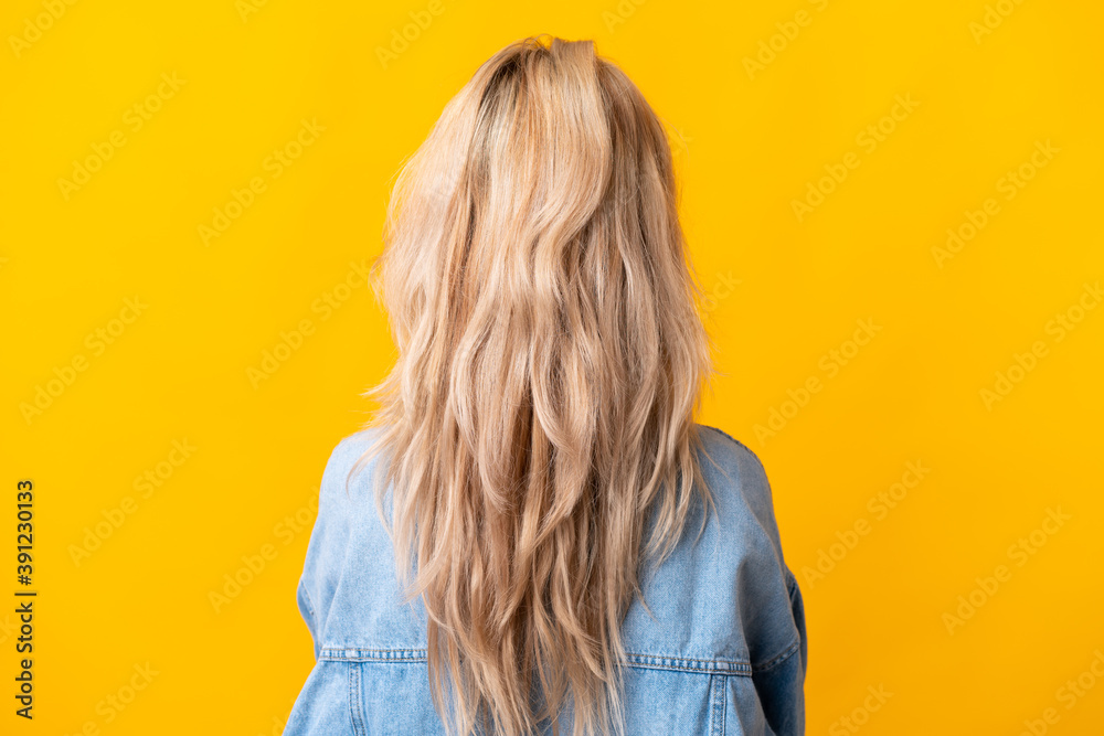 Fototapeta premium Young Russian woman isolated on yellow background in back position
