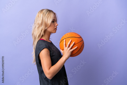Young Russian woman isolated on purple background playing basketball