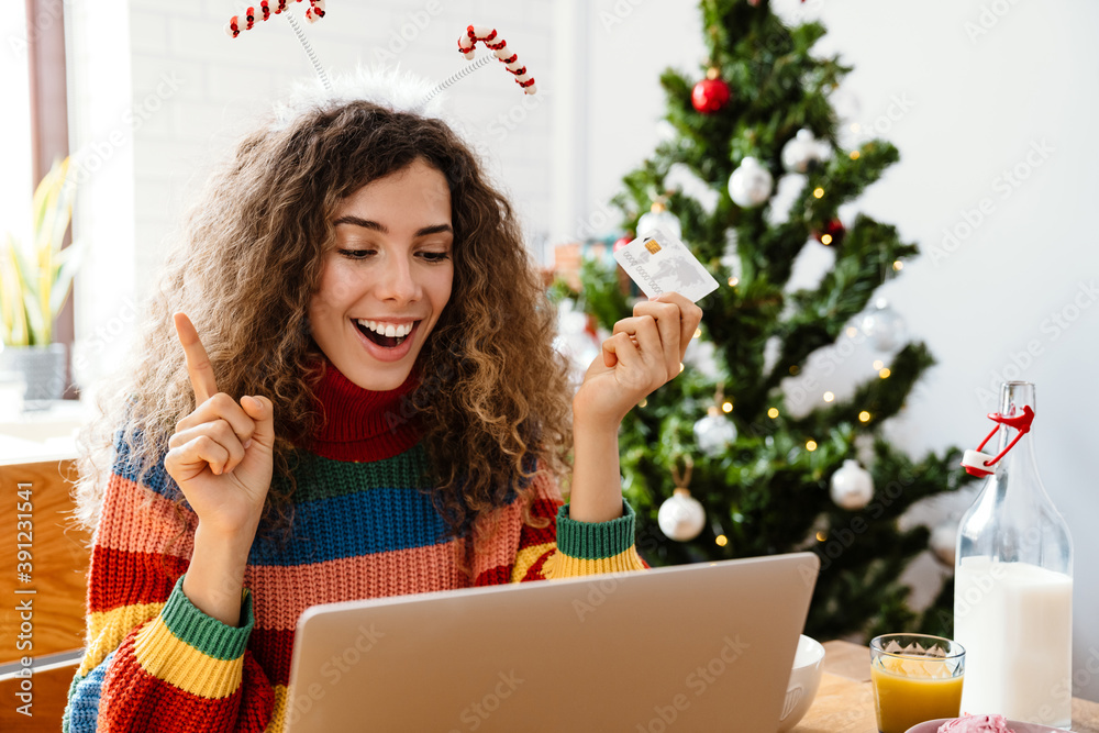 Excited woman using credit card and laptop while having breakfast Excited woman using credit card and laptop while having breakfast