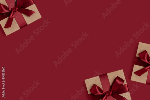 Frame made of gift boxes tied with ribbons on a red background with copy space. New Years composition.