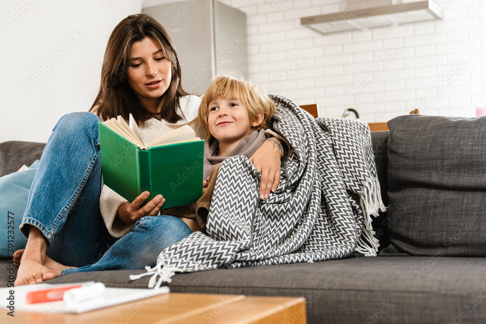 Woman reading a book at home for her son Woman reading a book at home for her son
