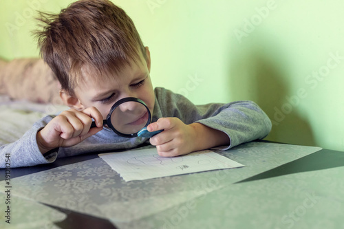 A little boy studies the world by looking at objects through a magnifying glass.