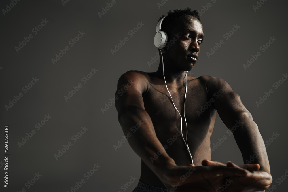 Obraz premium African american sportsman using headphones while stretching his hands