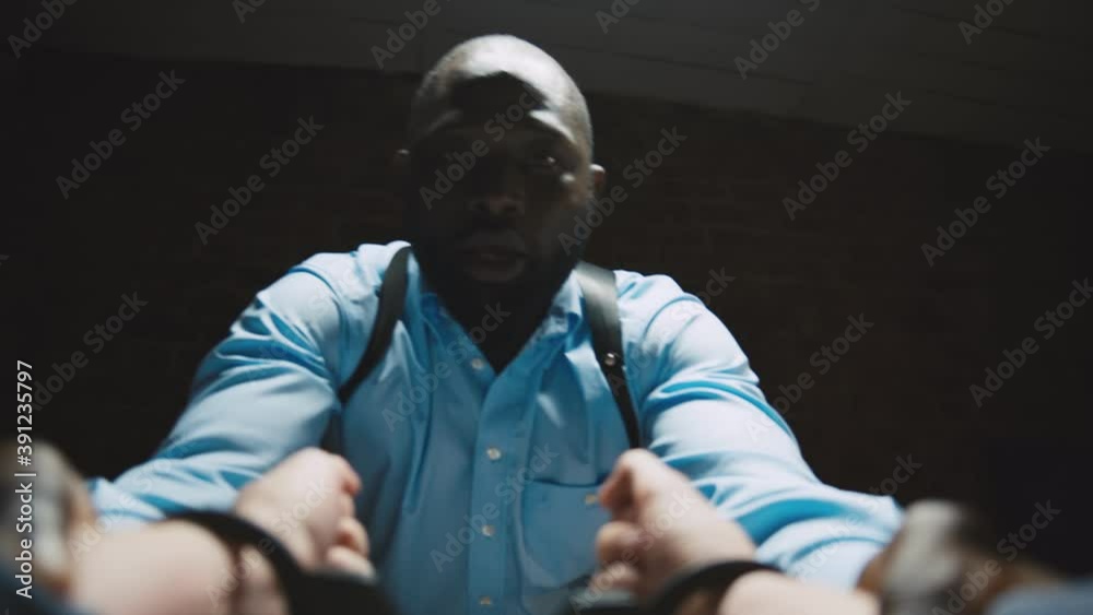 Angry black detective interviewing criminal in interrogation room Angry black detective interviewing criminal in interrogation room