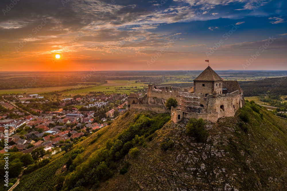 Sumeg, Hungary - Aerial view of the famous High Castle of Sumeg in Veszprem county at sunset with colorful clouds and dramatic colors of sunset at background on a summer afternoon