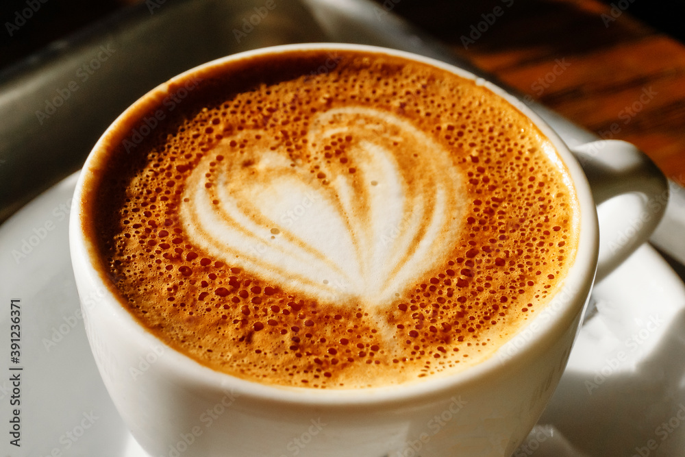 Cup of cappuccino coffee with milk foam and heart on a table in a cafe in the morning Cup of cappuccino coffee with milk foam and heart on a table in a cafe in the morning