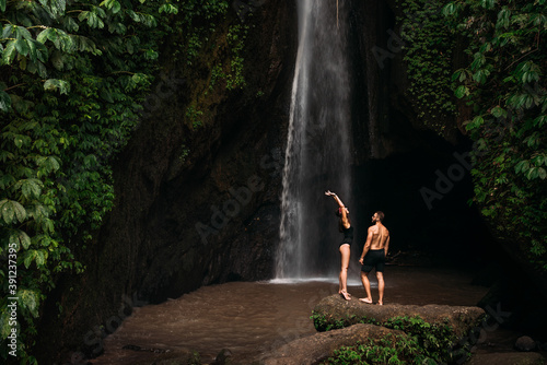 Beautiful couple at the waterfall. A couple in love travels to Indonesia on the island of Bali. A man and a woman at a waterfall in Indonesia. Vacation in Bali. Honeymoon trip. Copy space