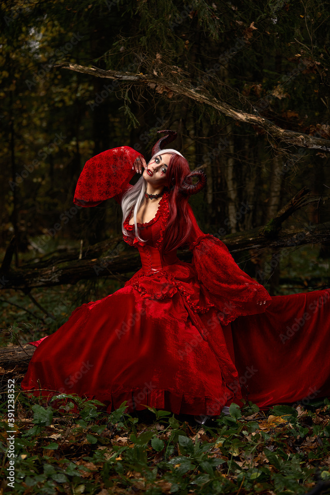 Stylish and fashionable model girl in the image of Maleficent posing among mystic forest - fairytale story, cosplay. Halloween