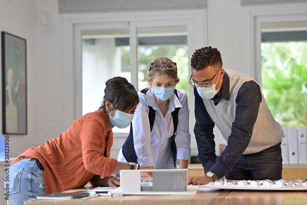 Team of architects working on project, wearing face mask in office Team of architects working on project, wearing face mask in office
