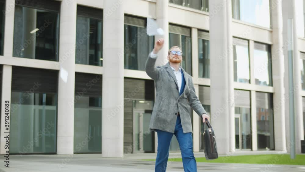 Businessman walking out office building and throwing paper celebrating transition to remote work Businessman walking out office building and throwing paper celebrating transition to remote work