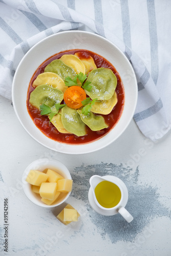 Ravioli with tomato sauce and grated parmesan cheese, above view on a white concrete background, vertical shot