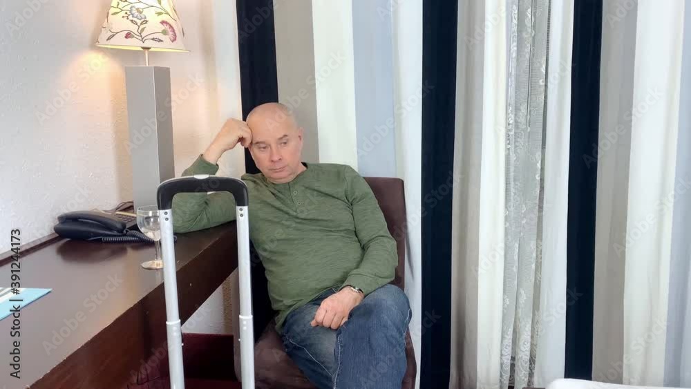 middle-aged man sits on a chair in an apartment, hotel room, drinks alcohol, ponders, the concept of business travel, tourism, difficulties in life middle-aged man sits on a chair in an apartment, hotel room, drinks alcohol, ponders, the concept of business travel, tourism, difficulties in life