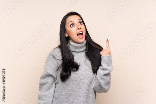 Young Colombian girl over isolated background pointing up and surprised