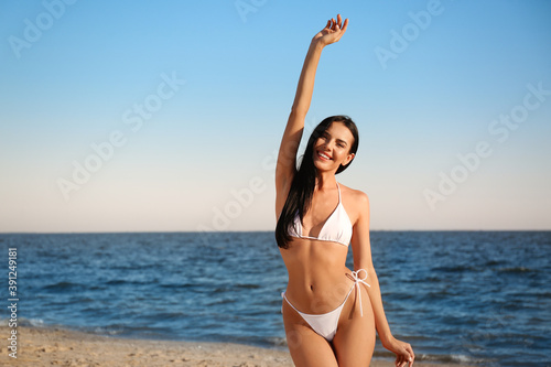 Beautiful young woman in white stylish bikini on beach © New Africa