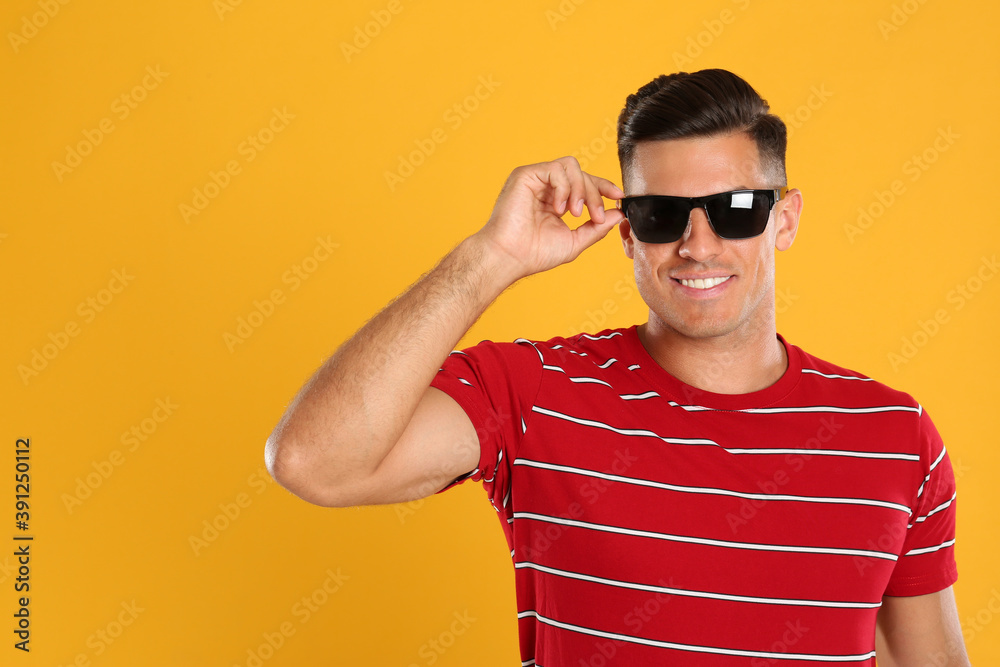 Handsome man wearing sunglasses on yellow background Handsome man wearing sunglasses on yellow background