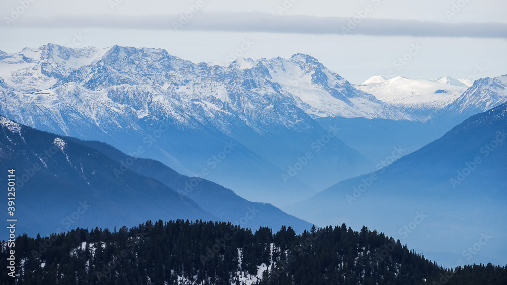 Snow-capped mountain ranges in BC, Canada, bathed in blue light (early winter).