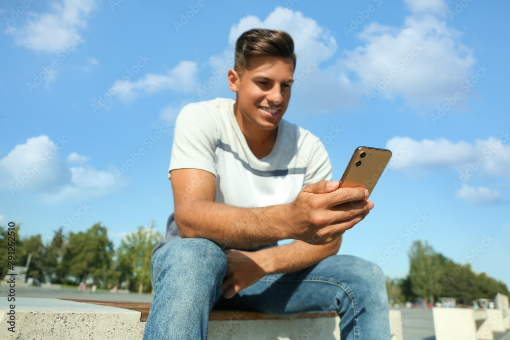 Fototapeta premium Handsome man using modern mobile phone outdoors, focus on hand