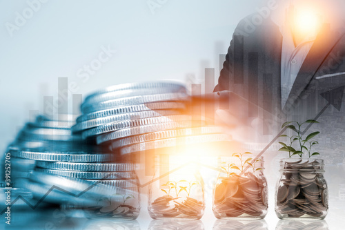 Saving and stock market investment concept , double exposure of Businessman using tablet for stock market trading and growth coins stacking in saving jar.