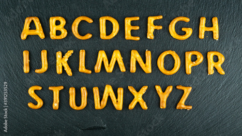 Obraz na płótnie snack alphabet made of salty sticks letters on black stone background. Pretzels, salty snacks text. w salonie