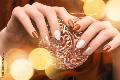 Christmas nail design. Female hands with red and golden manicure. Female hold golden xmas toy orb. Happy New Year. photo