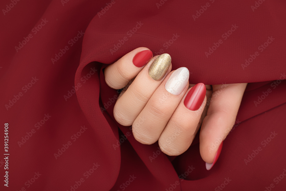 Female hand with red, gold and white nail design. Golden nail polish  manicure. Woman hand on red fabric background Stock Photo | Adobe Stock