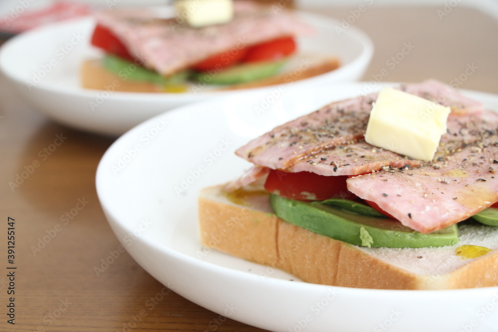パンとバターとトマトとアボカドをのせた白いお皿 パンとバターとトマトとアボカドをのせた白いお皿