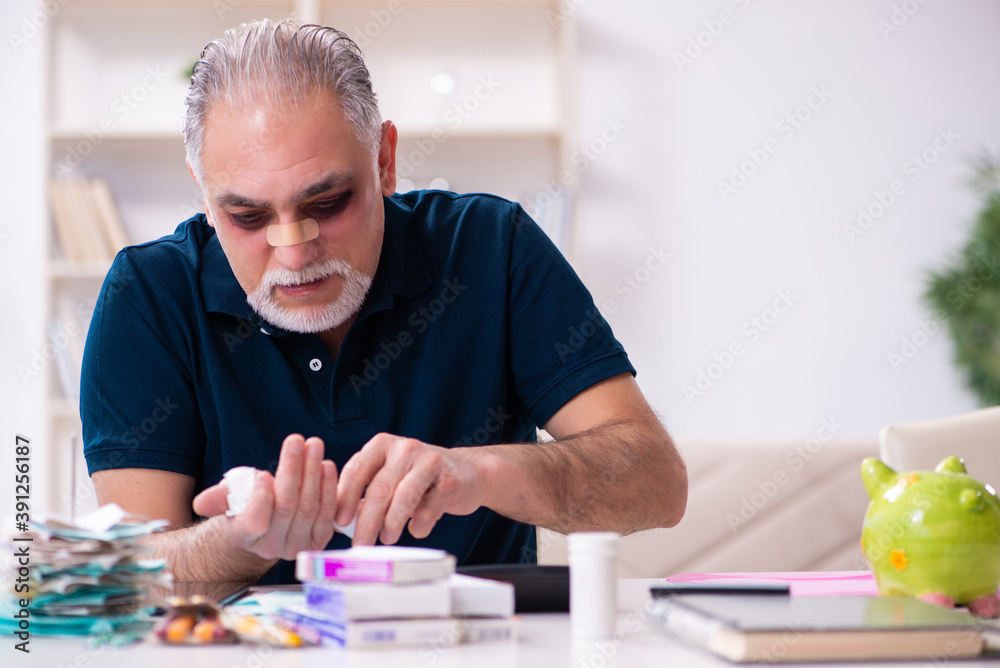 Old injured man in budget planning concept Old injured man in budget planning concept