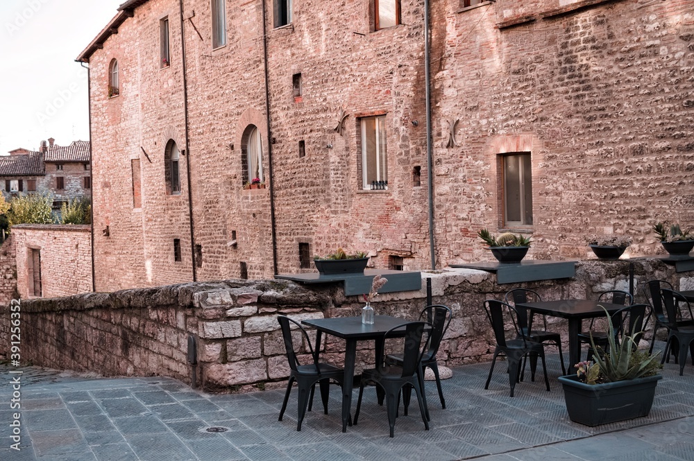 Tables and chairs of a bar in an alley of a medieval village (Gubbio, Umbria, Italy)