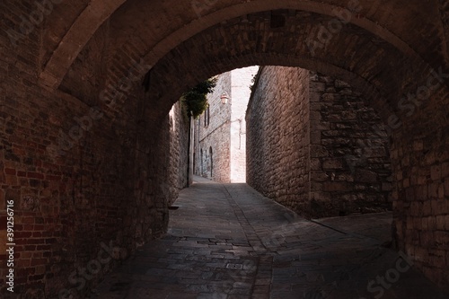 The view of an ancient alley under an architectural arch in a medieval Italian village  Gubbio  Umbria  Italy 