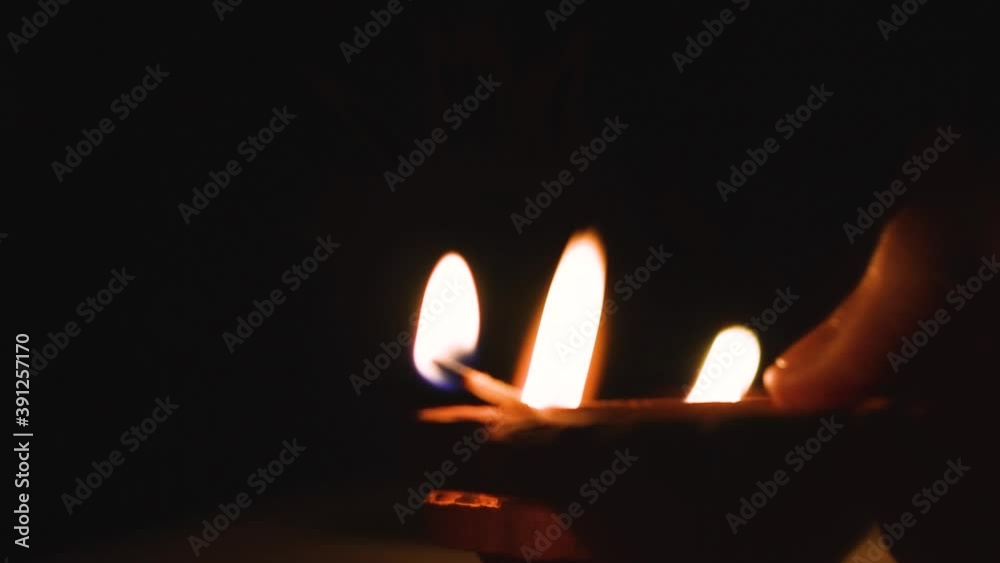 Close up shot of hand igniting Diya with lit diya during celebration of Indian festival Diwali Close up shot of hand igniting Diya with lit diya during celebration of Indian festival Diwali
