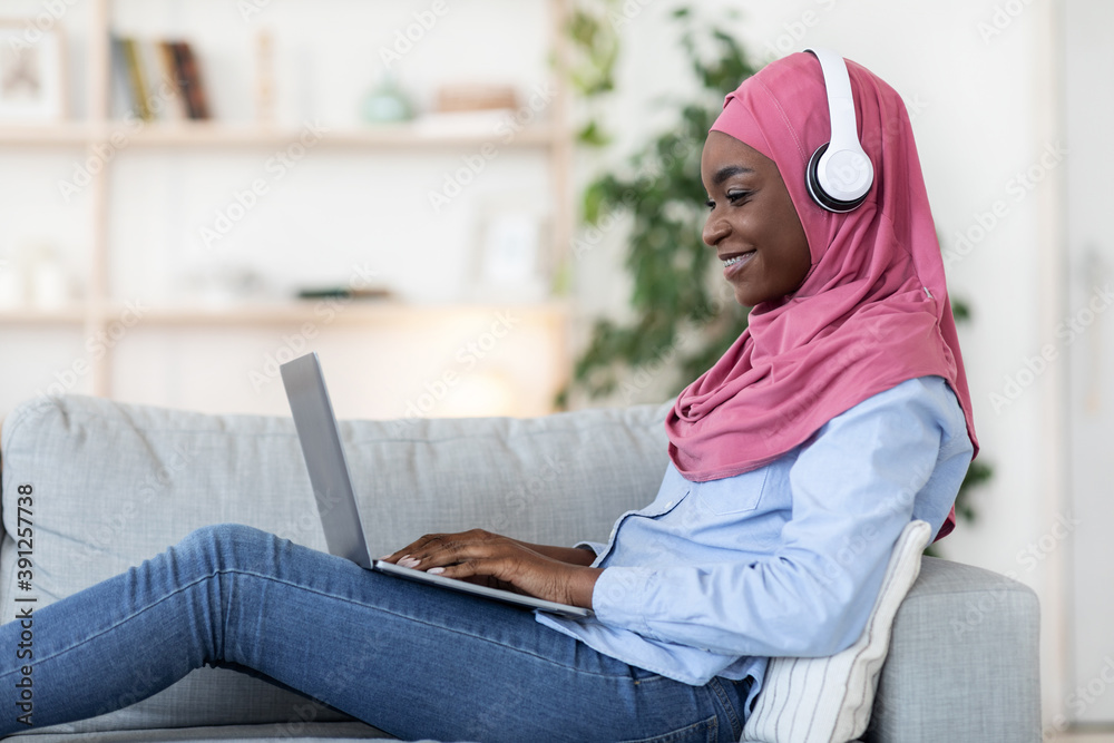 Freelance Concept. Black Muslim Woman Working On Laptop At Home, Side View Freelance Concept. Black Muslim Woman Working On Laptop At Home, Side View