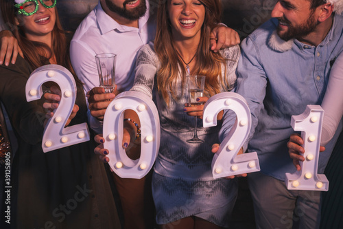 Group of friends holding illuminative numbers 2021 at New Year's party