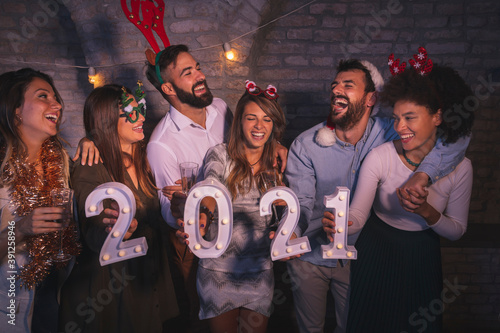 Friends holding illuminative numbers 2021 at New Year's party
