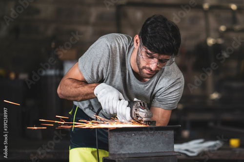 Photos A mechanic wearing safety equipment and operating angle grinder - Metal factory