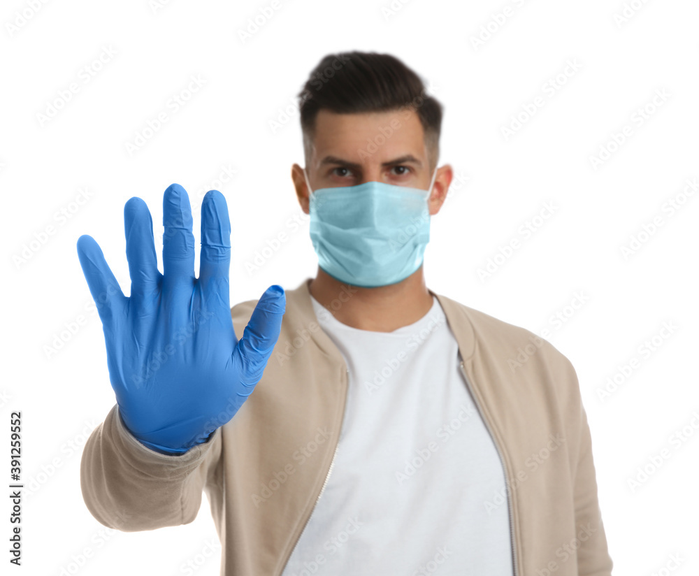 Man in protective face mask and medical gloves showing stop gesture against white background, focus on hand Man in protective face mask and medical gloves showing stop gesture against white background, focus on hand