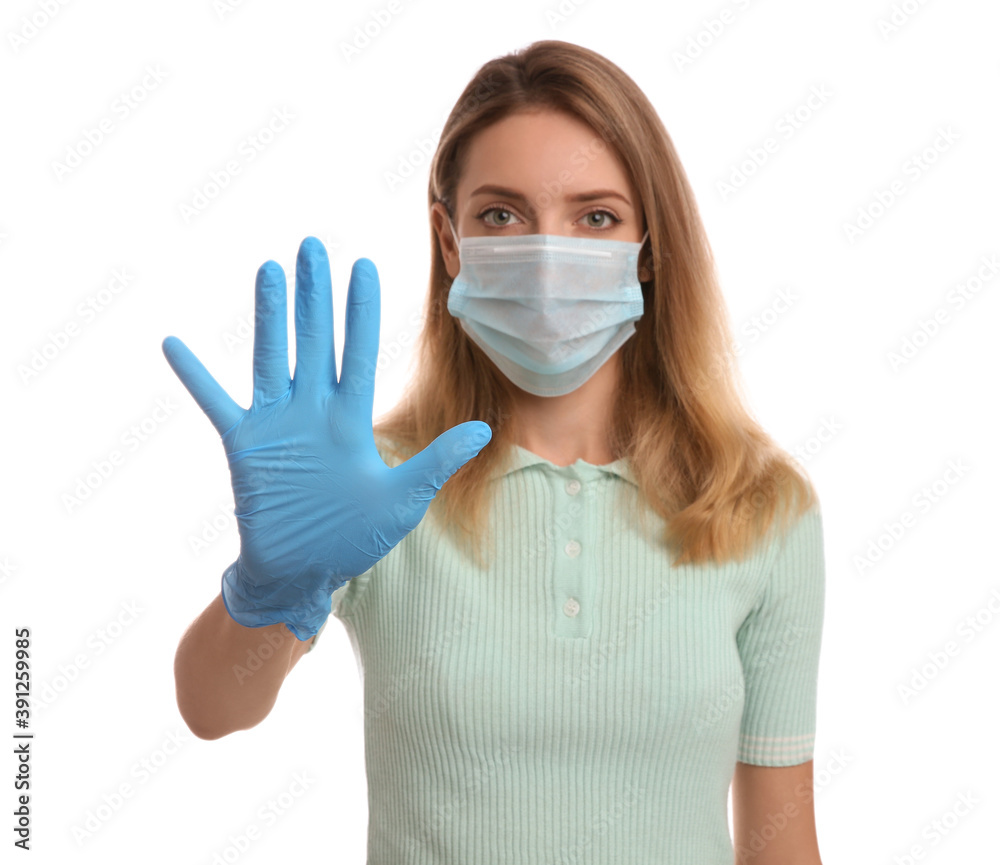 Young woman in medical gloves and protective face mask showing stop gesture against white background, focus on hand Young woman in medical gloves and protective face mask showing stop gesture against white background, focus on hand