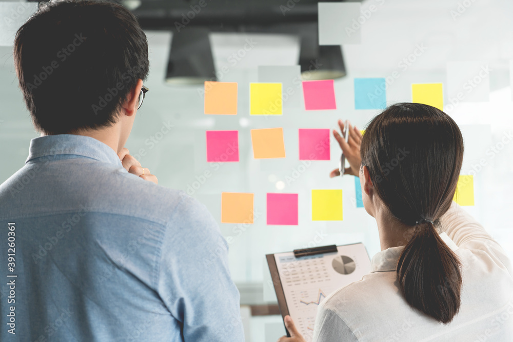 Obraz premium Business manager showing idea for her team and stick many memo paper on glass window to success working in business meeting creative office, planning and management concept.