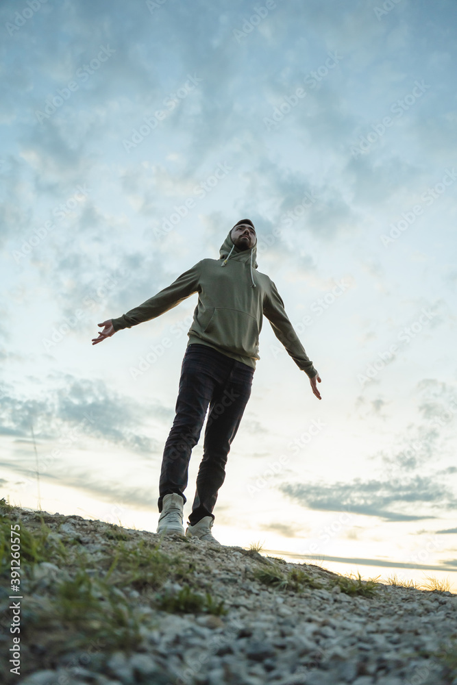 Young man in green sweatshirt stands with arms outstretched Young man in green sweatshirt stands with arms outstretched