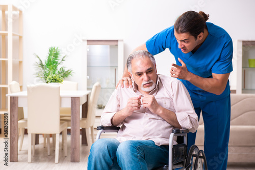 Old man in wheel-chair and young bad caregiver indoors