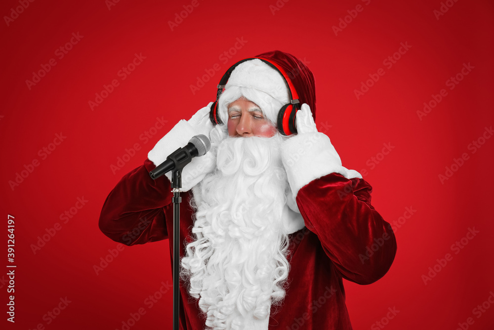 Santa Claus with headphones and microphone on red background. Christmas music