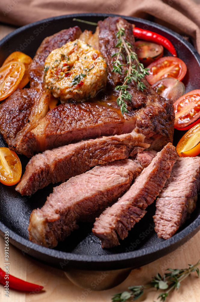 Fried beef steak with vegetables. A large piece of meat is sliced and garnished with fresh vegetables Fried beef steak with vegetables. A large piece of meat is sliced and garnished with fresh vegetables