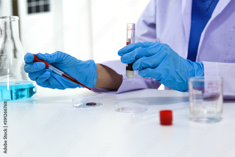 Scientist holding Coronavirus covid-19 infected blood sample tube DNA testing of the blood in the laboratory with blood sample collection tubes and syringe Coronavirus Covid-19 vaccine research. Scientist holding Coronavirus covid-19 infected blood sample tube DNA testing of the blood in the laboratory with blood sample collection tubes and syringe Coronavirus Covid-19 vaccine research.