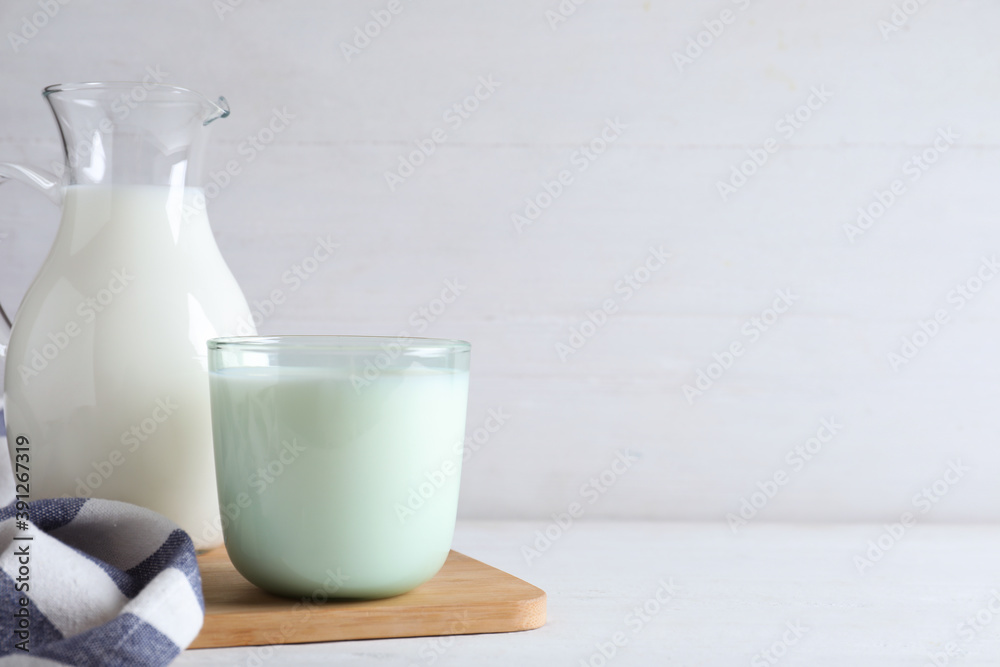 Jug and glass with fresh milk on white wooden table. Space for text Jug and glass with fresh milk on white wooden table. Space for text