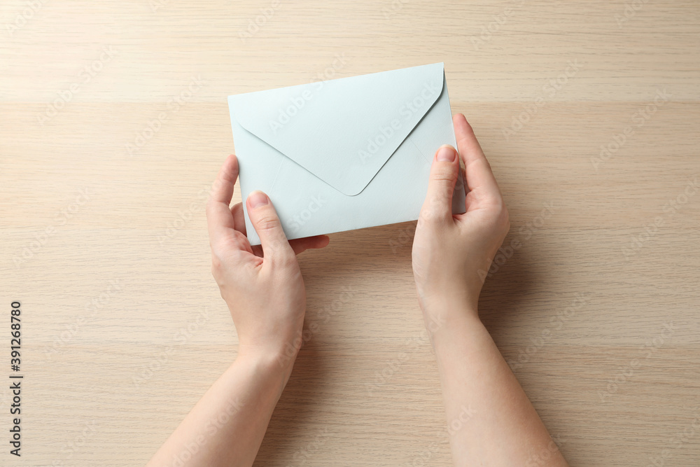 Woman with white paper envelope at wooden table, top view Woman with white paper envelope at wooden table, top view