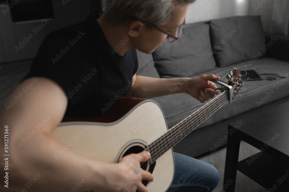 Fototapeta premium Man with white hair wearing glasses playing guitar at home