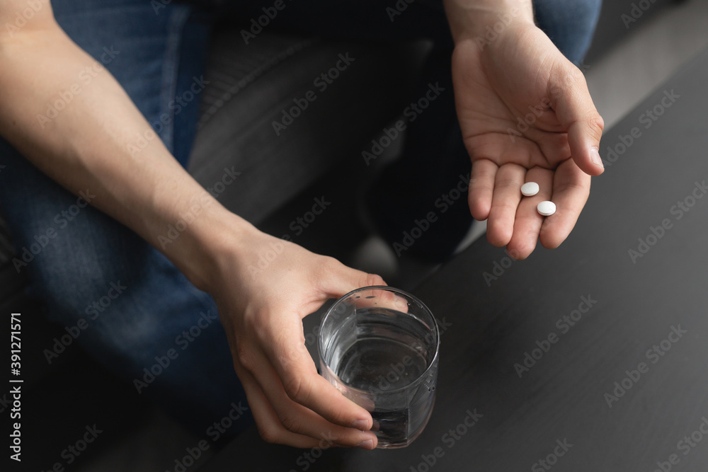 A man is sick and drinks pills with water