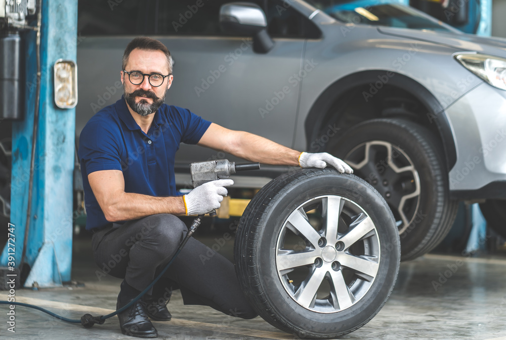 Professional car mechanic changing car wheel at Car maintenance and auto service garage. Professional car mechanic changing car wheel at Car maintenance and auto service garage.