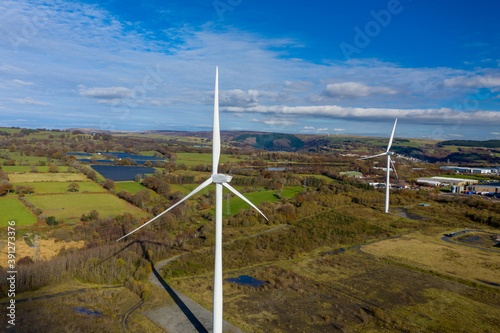 Aerial View of 2 large wind turbine stationary on beautiful welsh landscape. clean energy concept. close up shot